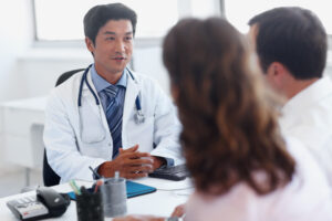 Physician speaking with couple in his office