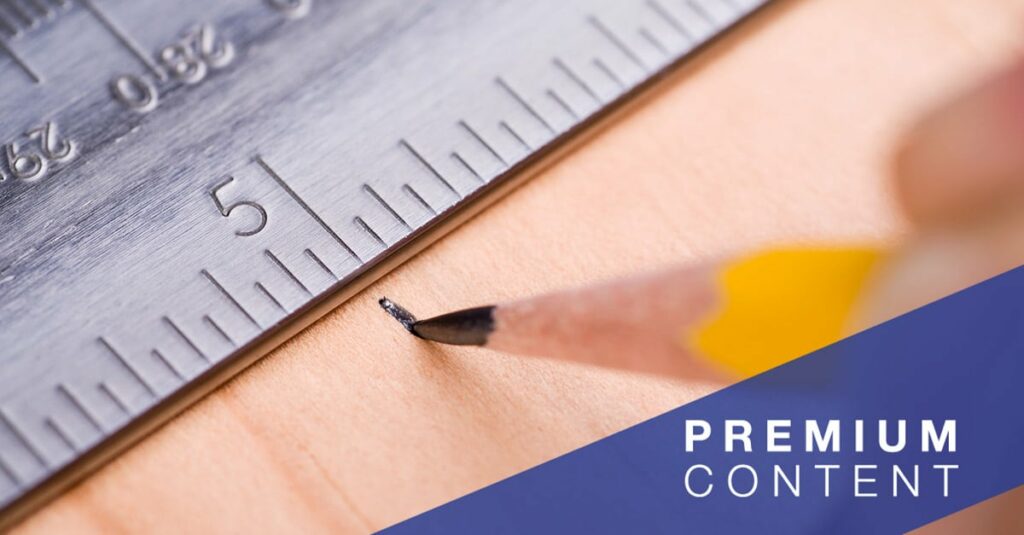 Close-up of person marking on a piece of wood a measurement indicated by a ruler