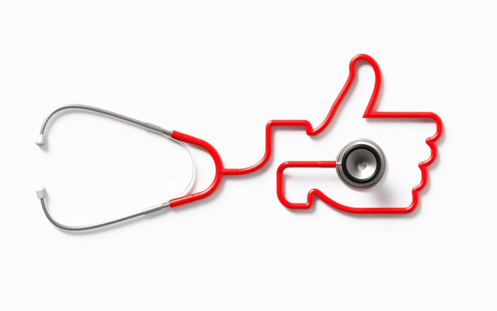 Red Stethoscope Forming A Thumb Up Symbol On White Background