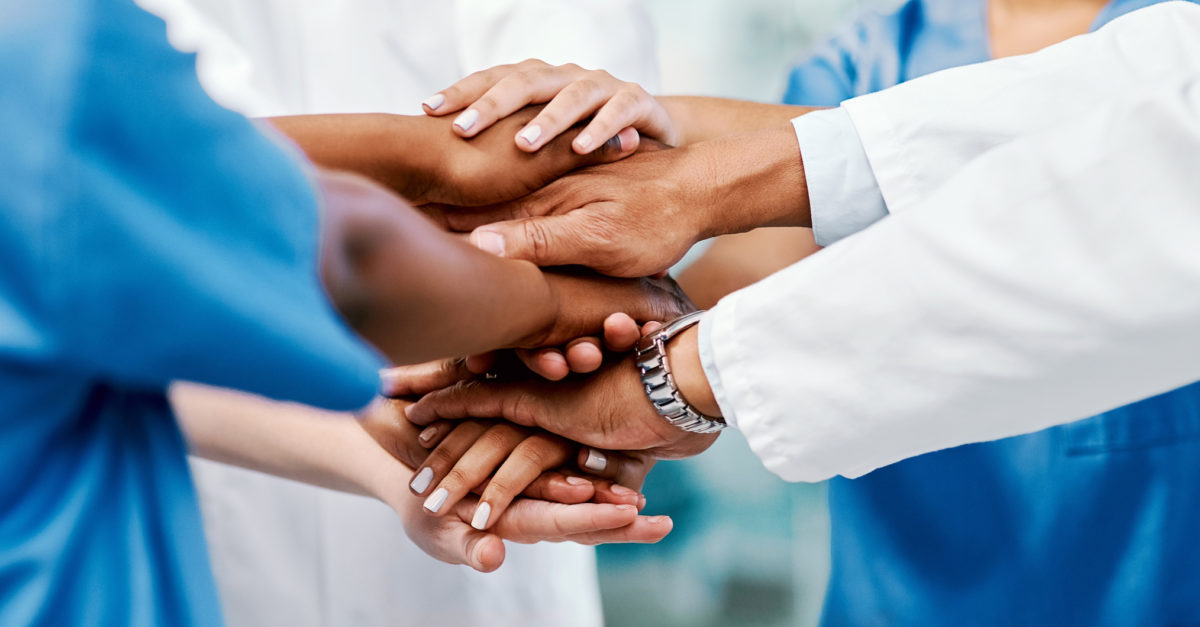 Doctors, nurses, and other healthcare employees putting their hands in a circle