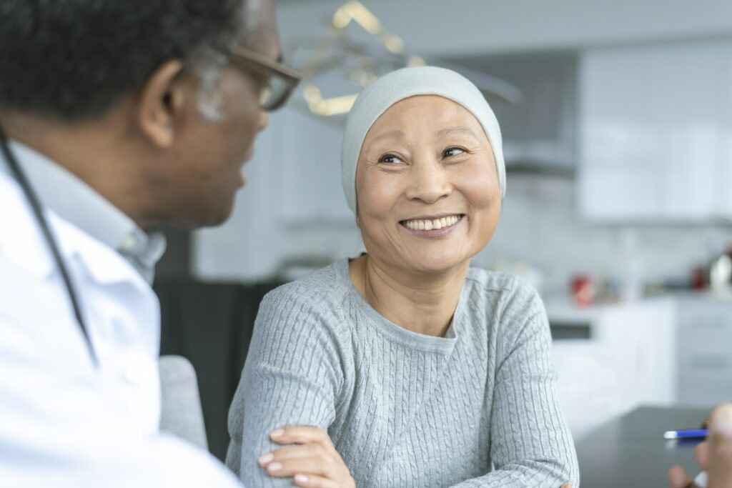 Cancer patient smiles as she speaks with her doctor about treatment