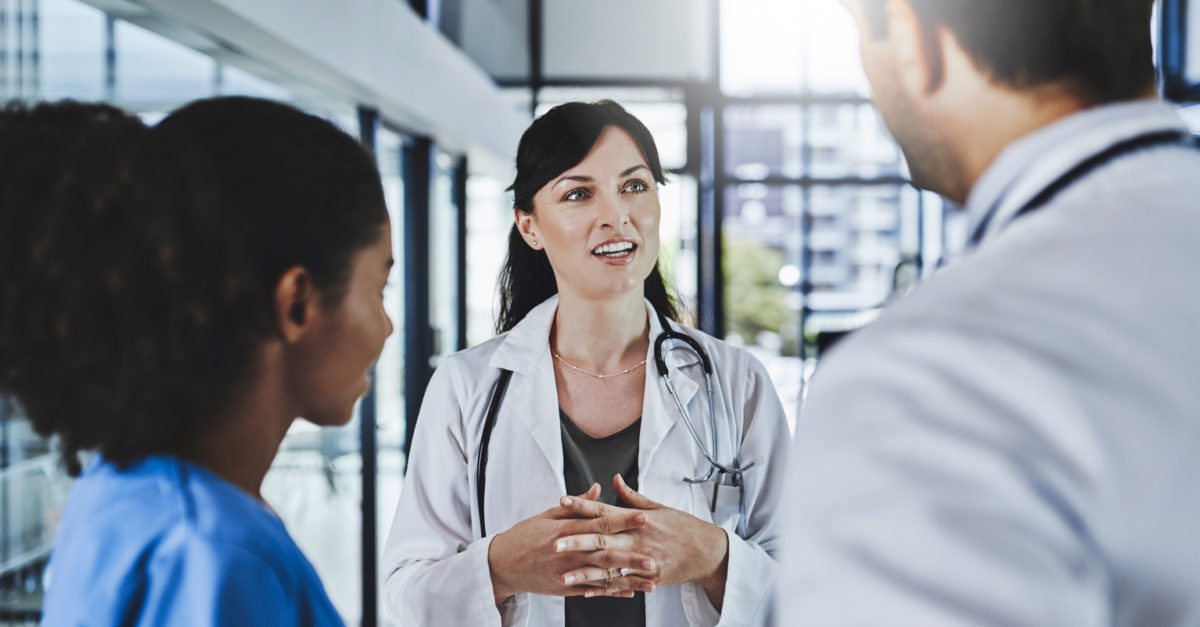 Healthcare organization leader talking to two employees about better engaging with employees