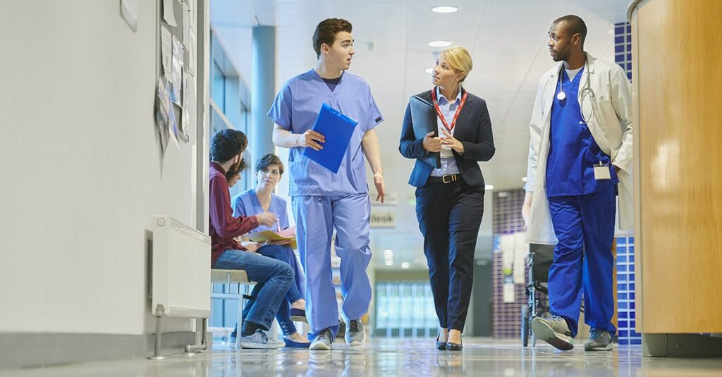 Doctor, nurse, and hospital leader walking down hall.