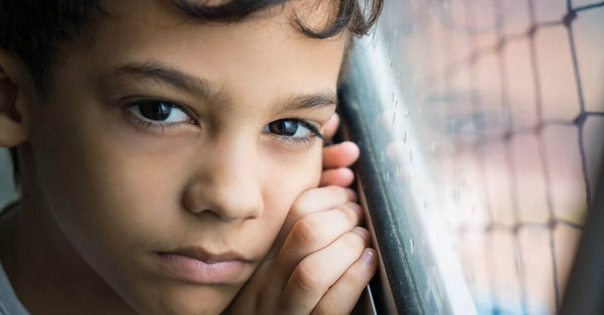 Child staring pensively by window