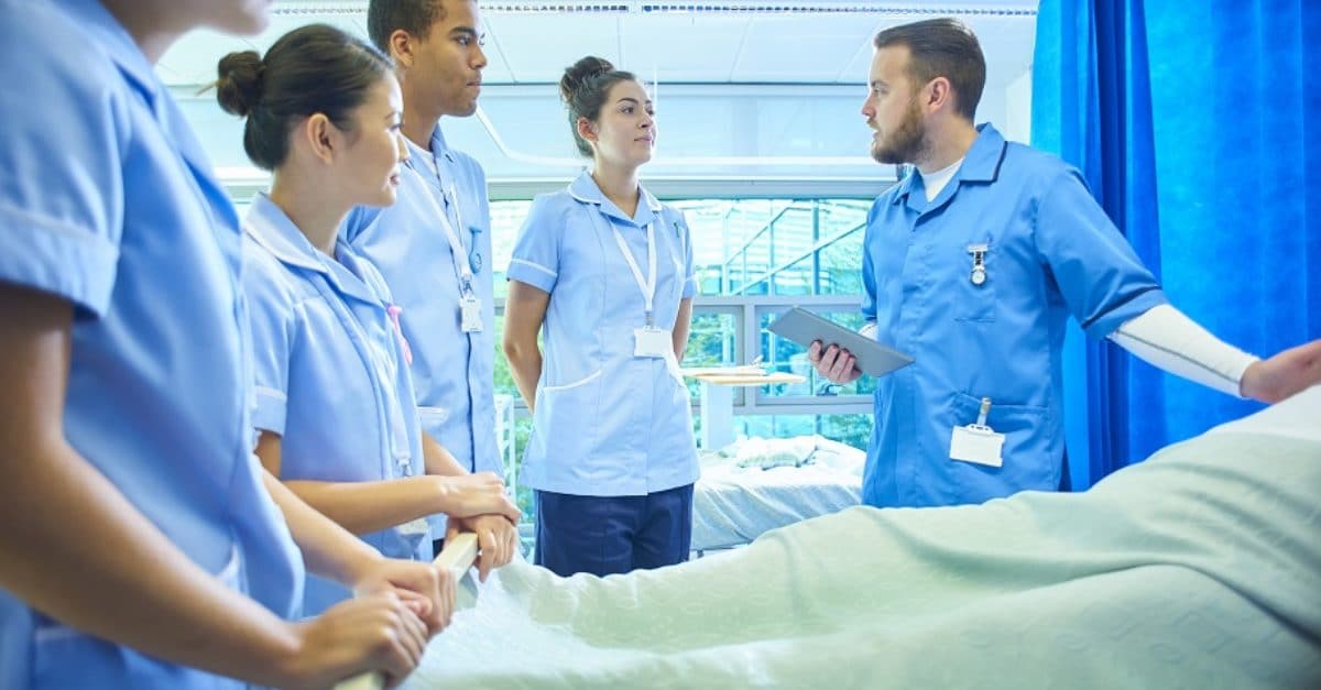 Group of nurses gathered around hospital bed