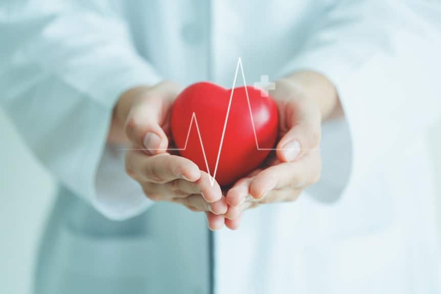 Doctor holding red heart ball with heartbeat